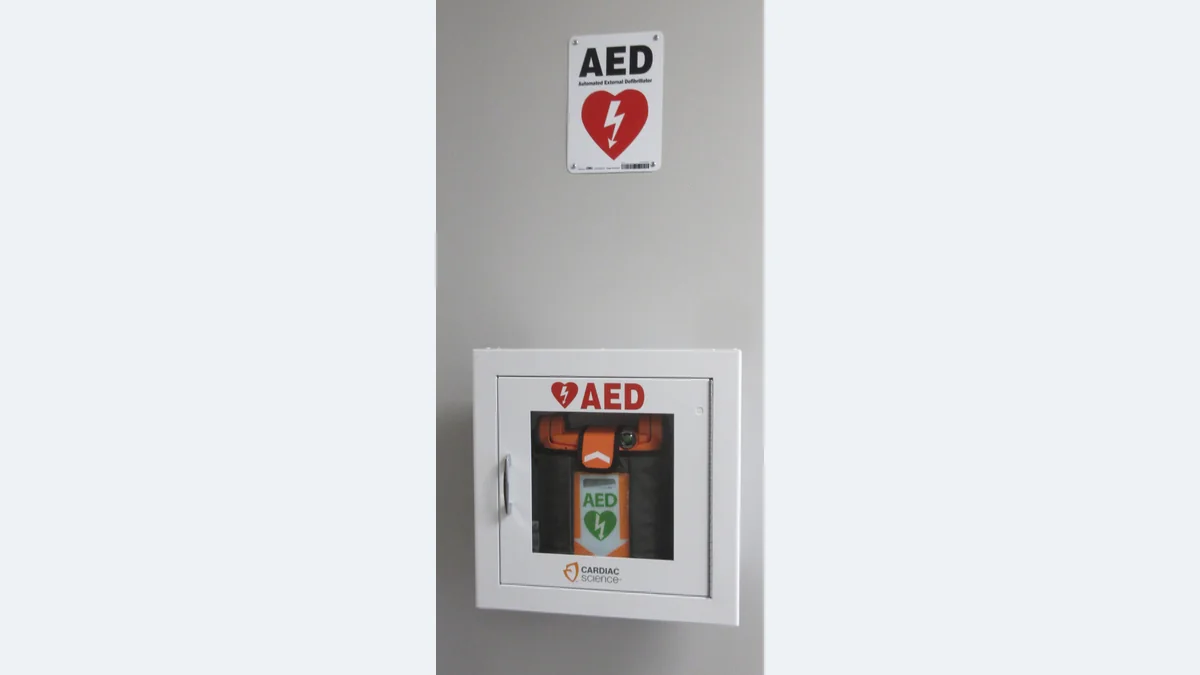 An AED stored in a marked wall compartment